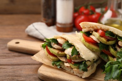 Photo of Delicious pita sandwich with grilled vegetables and parsley on wooden table, closeup. Space for text