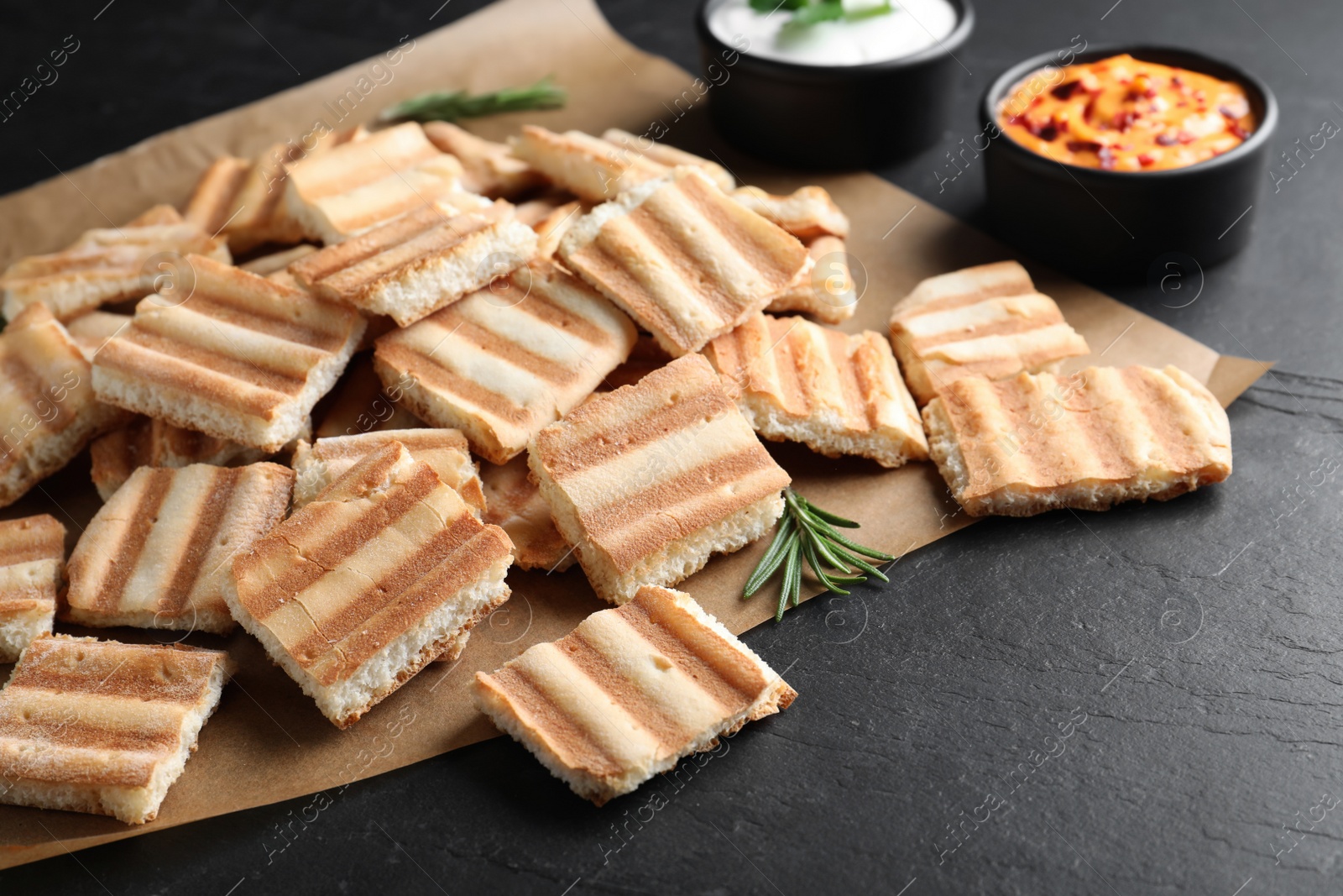 Photo of Delicious pita chips and sauce on black table