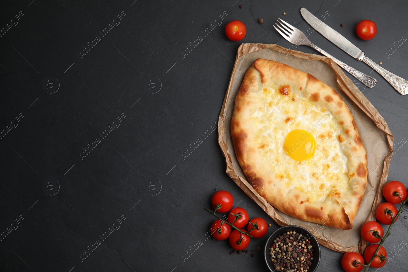 Photo of Fresh delicious Adjarian khachapuri served on black table, flat lay. Space for text