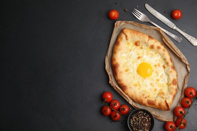 Fresh delicious Adjarian khachapuri served on black table, flat lay. Space for text
