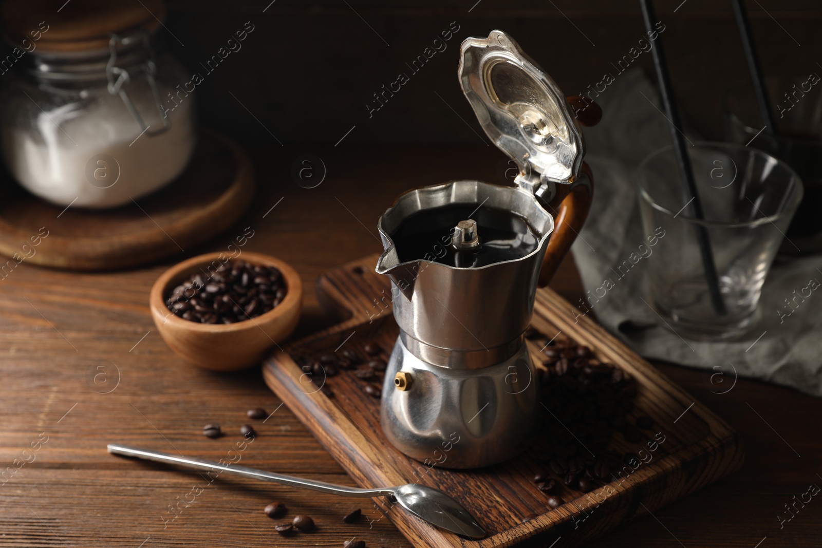 Photo of Brewed coffee in moka pot and beans on wooden table
