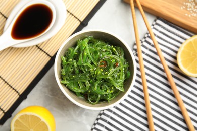 Japanese seaweed salad served on light marble table, flat lay