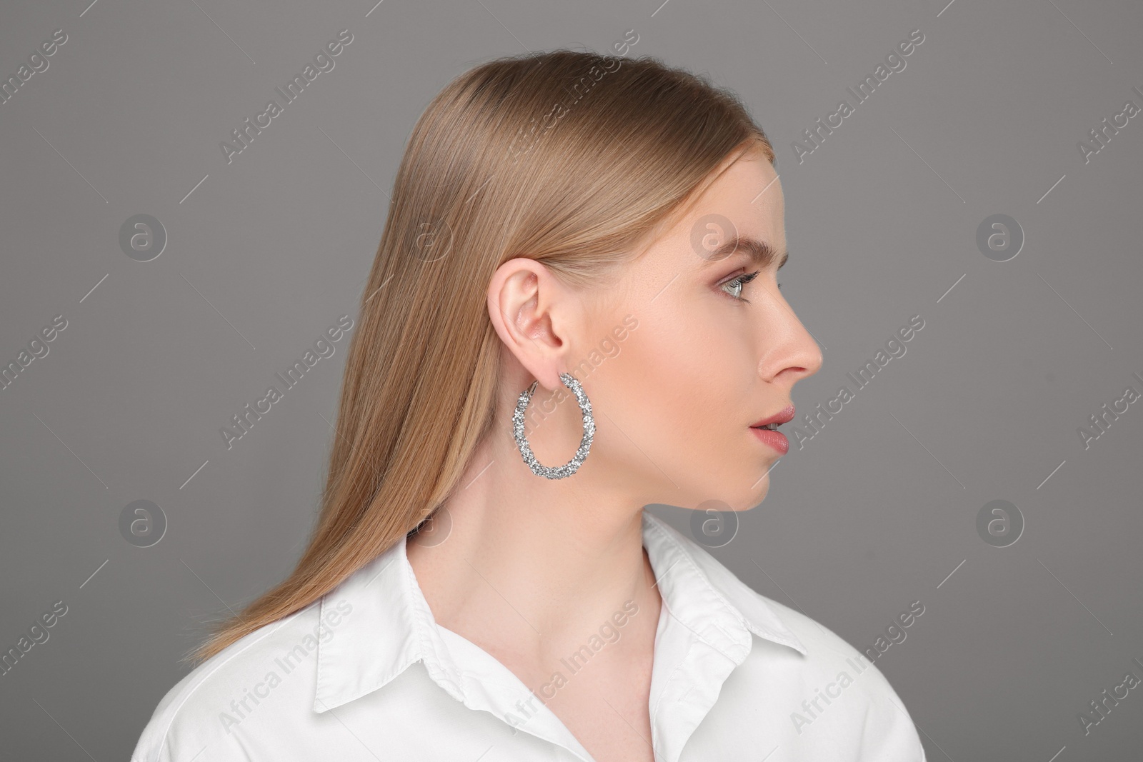 Photo of Beautiful young woman with elegant earrings on gray background