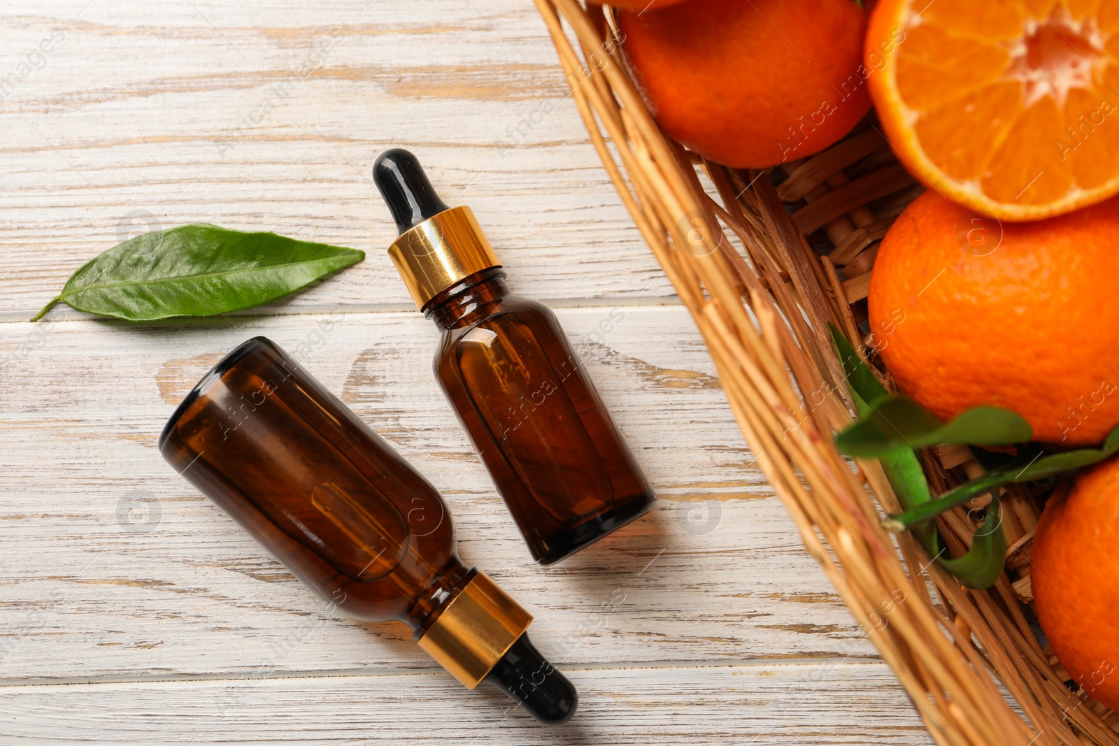 Photo of Bottle of tangerine essential oil and fresh fruits on white wooden table, flat lay