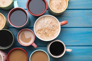 Photo of Many cups of different coffee drinks on light blue wooden table, flat lay