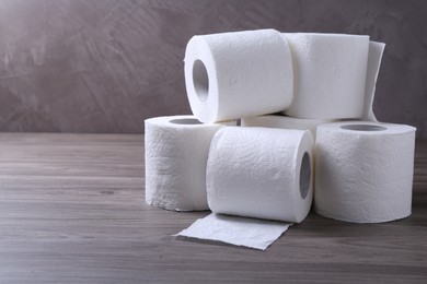 Photo of Soft toilet paper rolls on wooden table. Space for text