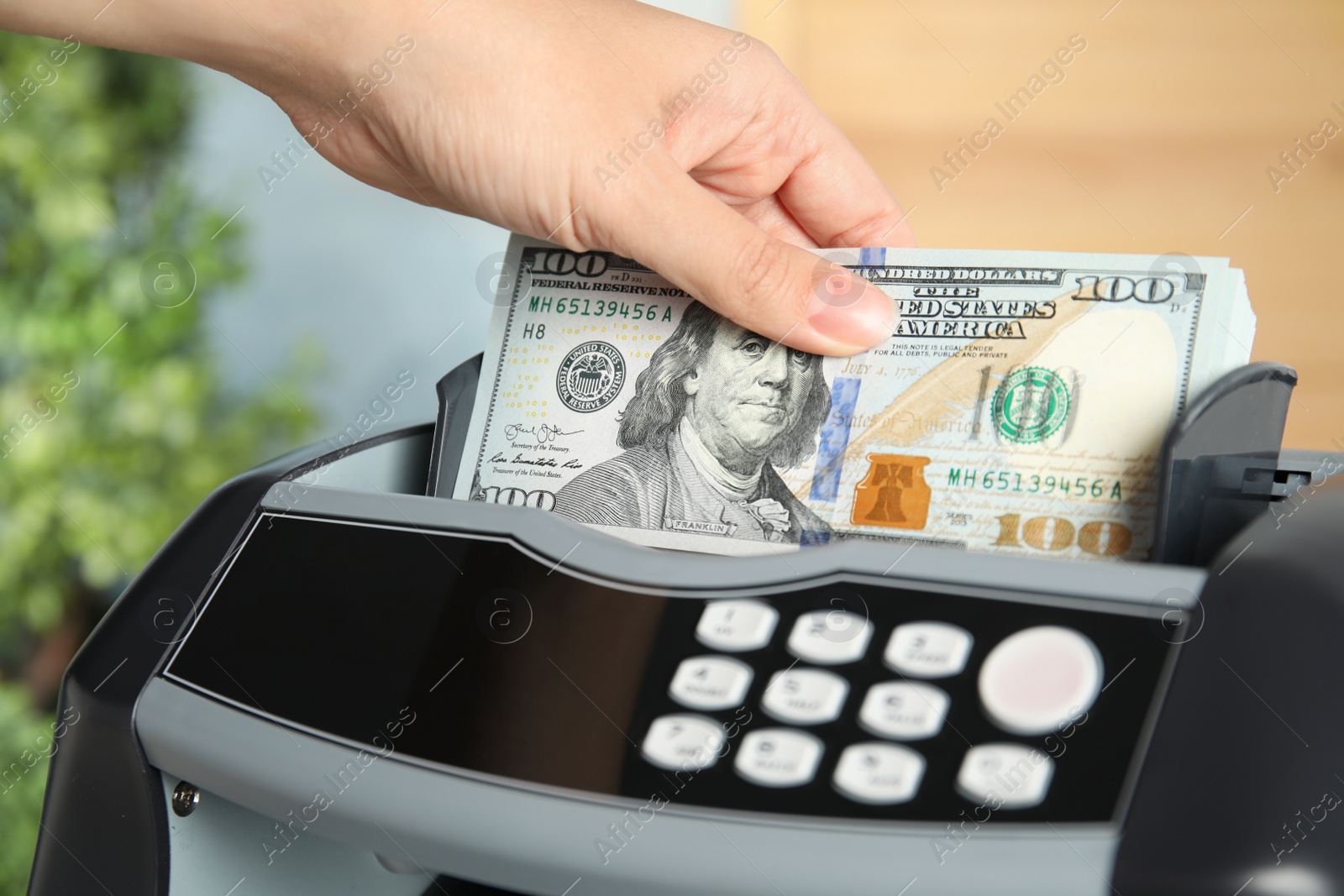 Photo of Woman putting money into counting machine indoors, closeup