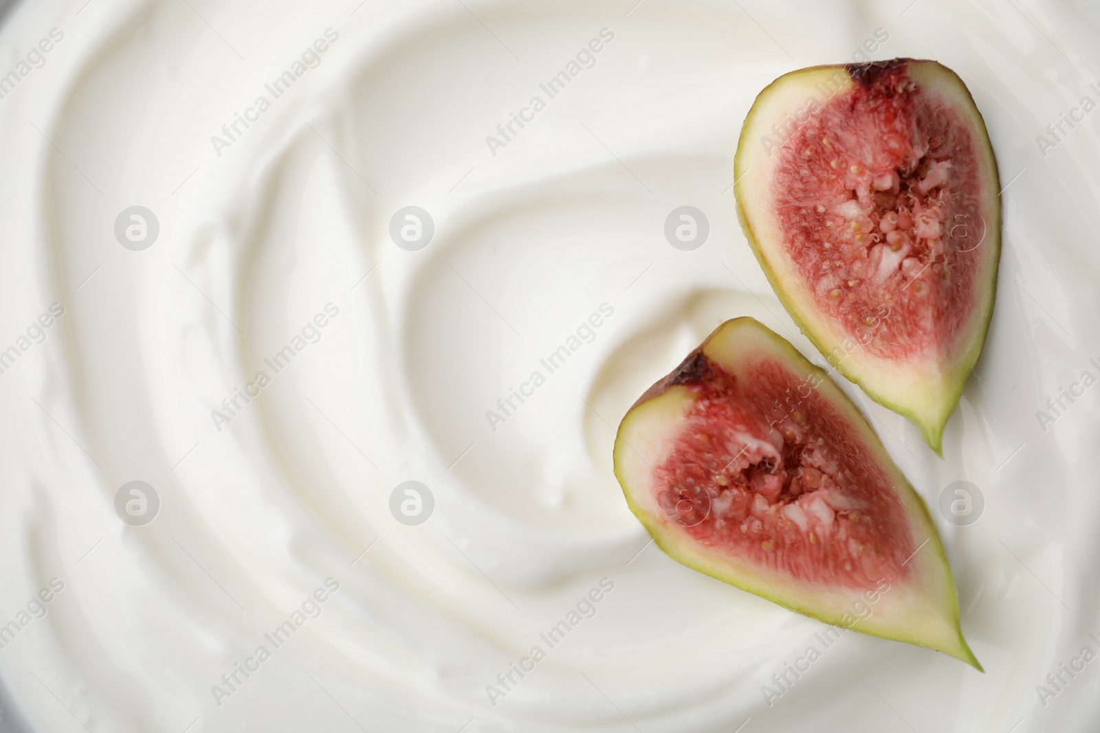 Photo of Tasty yogurt with cut fig as background, top view. Space for text