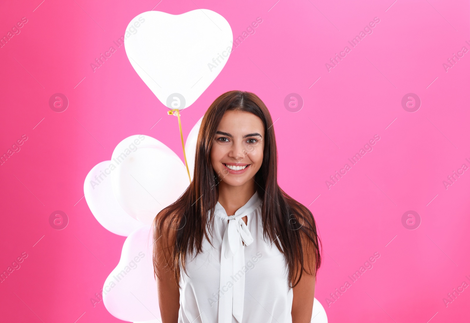 Photo of Young woman with air balloons on pink background. Celebration of Saint Valentine's Day