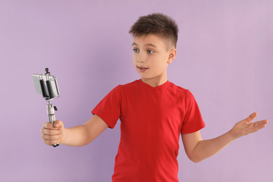 Photo of Cute little blogger recording video on violet background