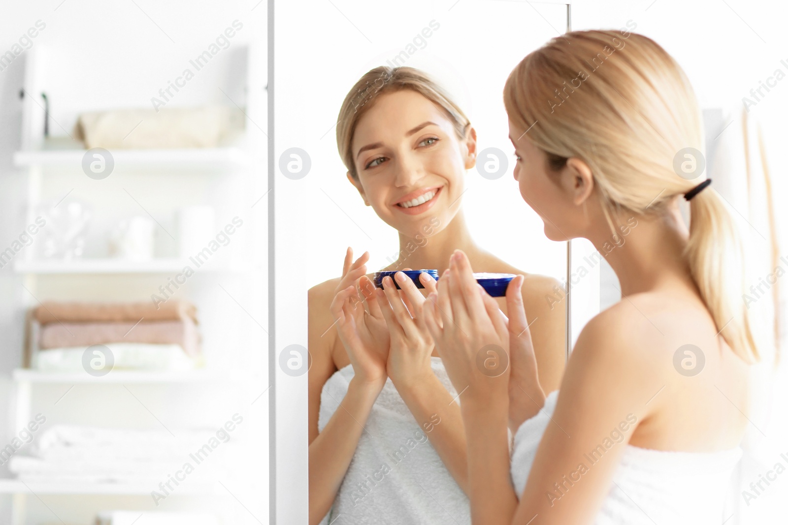 Photo of Young woman with jar of cream at home