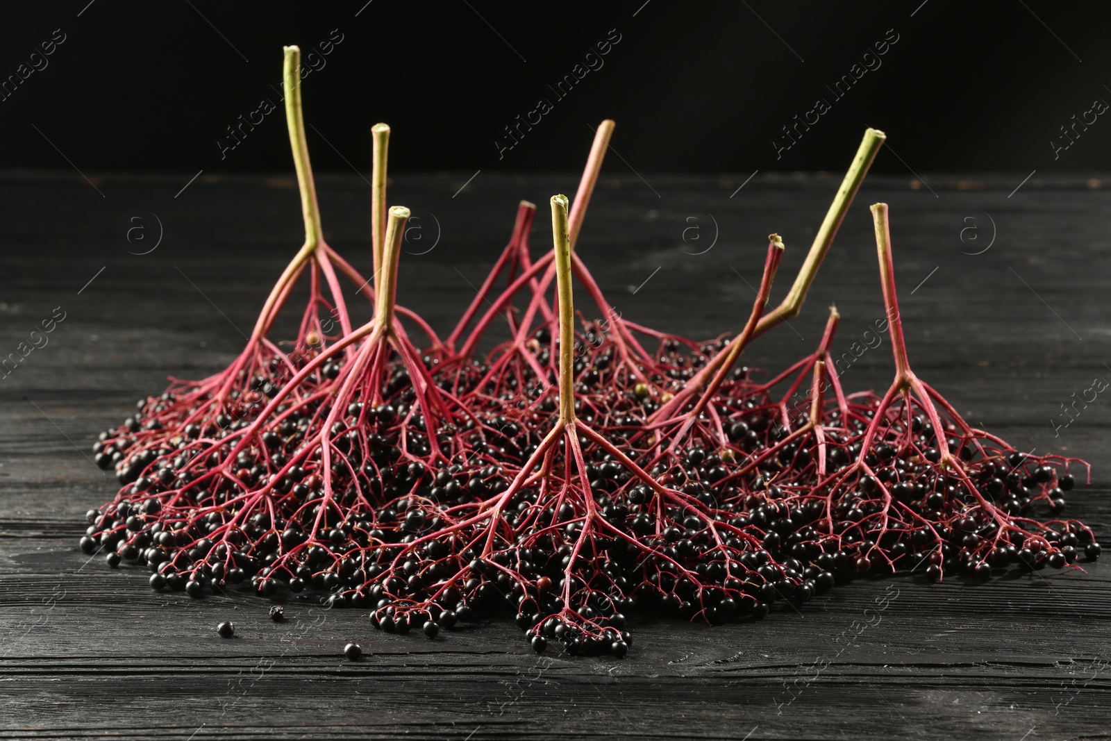 Photo of Bunches of ripe elderberries (Sambucus) on black wooden table