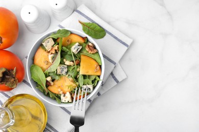 Tasty salad with persimmon, blue cheese and walnuts served on white marble table, flat lay. Space for text