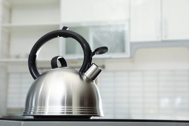 Modern kettle with whistle on stove in kitchen, space for text