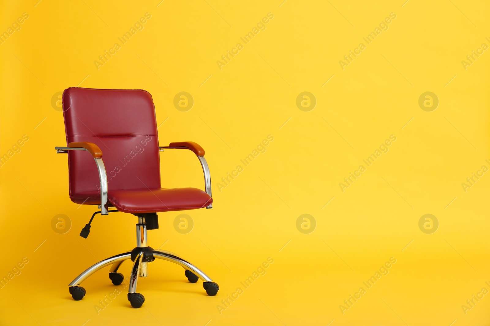 Photo of Modern office chair on yellow background. Space for text