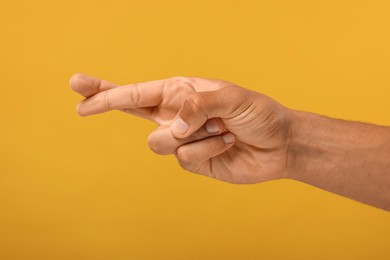 Photo of Man crossing his fingers on orange background, closeup
