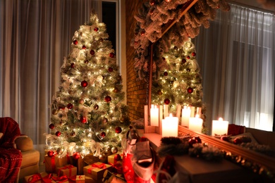 Photo of Stylish room interior with beautiful Christmas tree and gifts at night