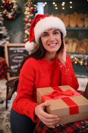 Photo of Beautiful woman with gift box in decorated cafe. Christmas celebration
