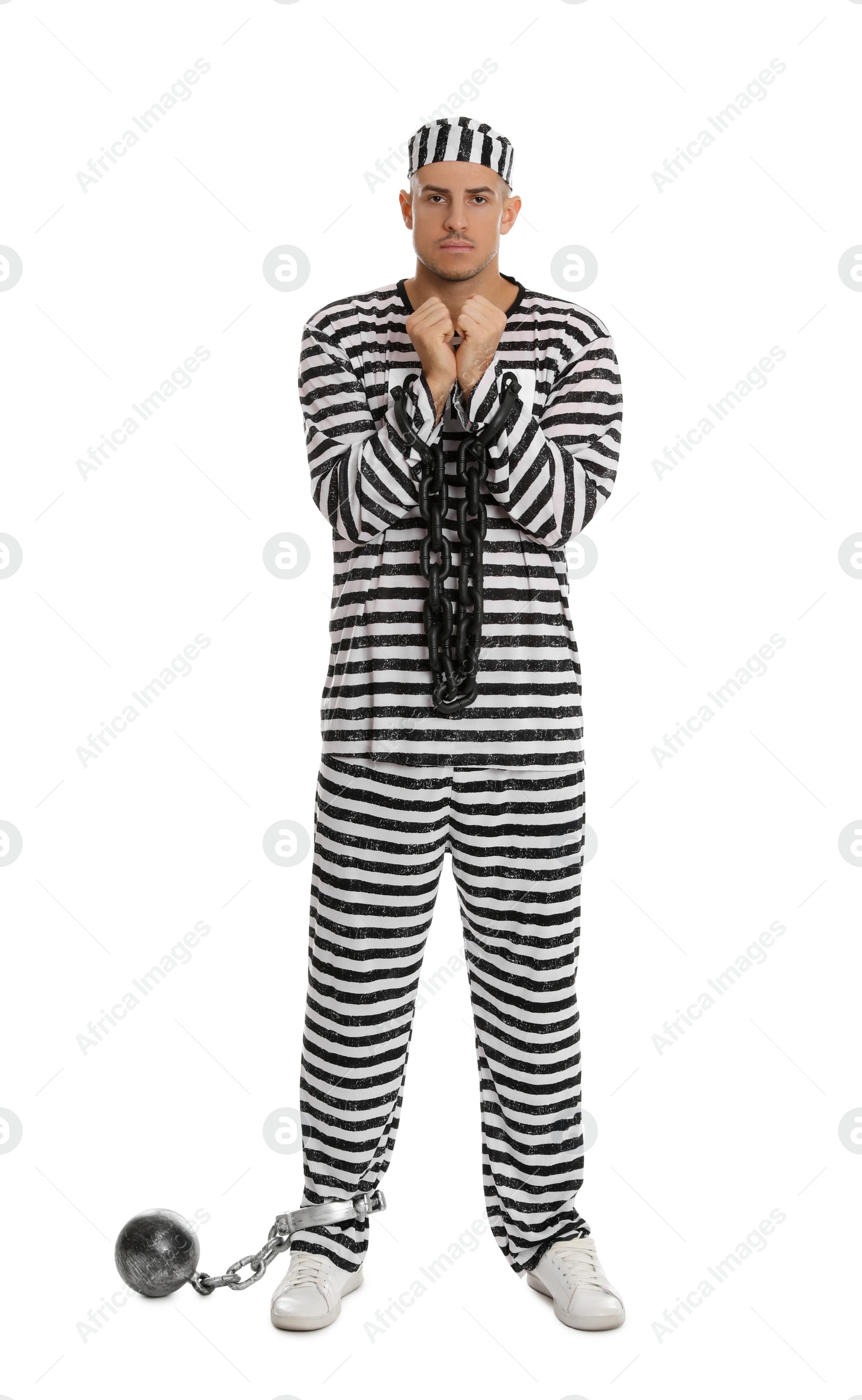 Photo of Prisoner in striped uniform with chained hands and metal ball on white background