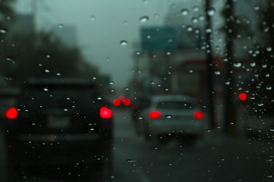 Road on rainy day, view through car window with water drops