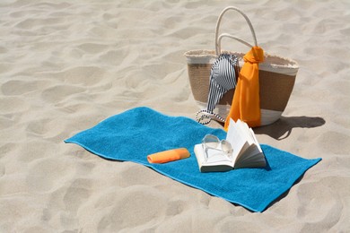 Blue towel, bag and beach accessories on sand