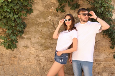 Young couple wearing white t-shirts near stone wall on street