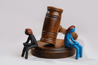 Divorce concept. Plasticine people figures and wooden gavel on light grey background