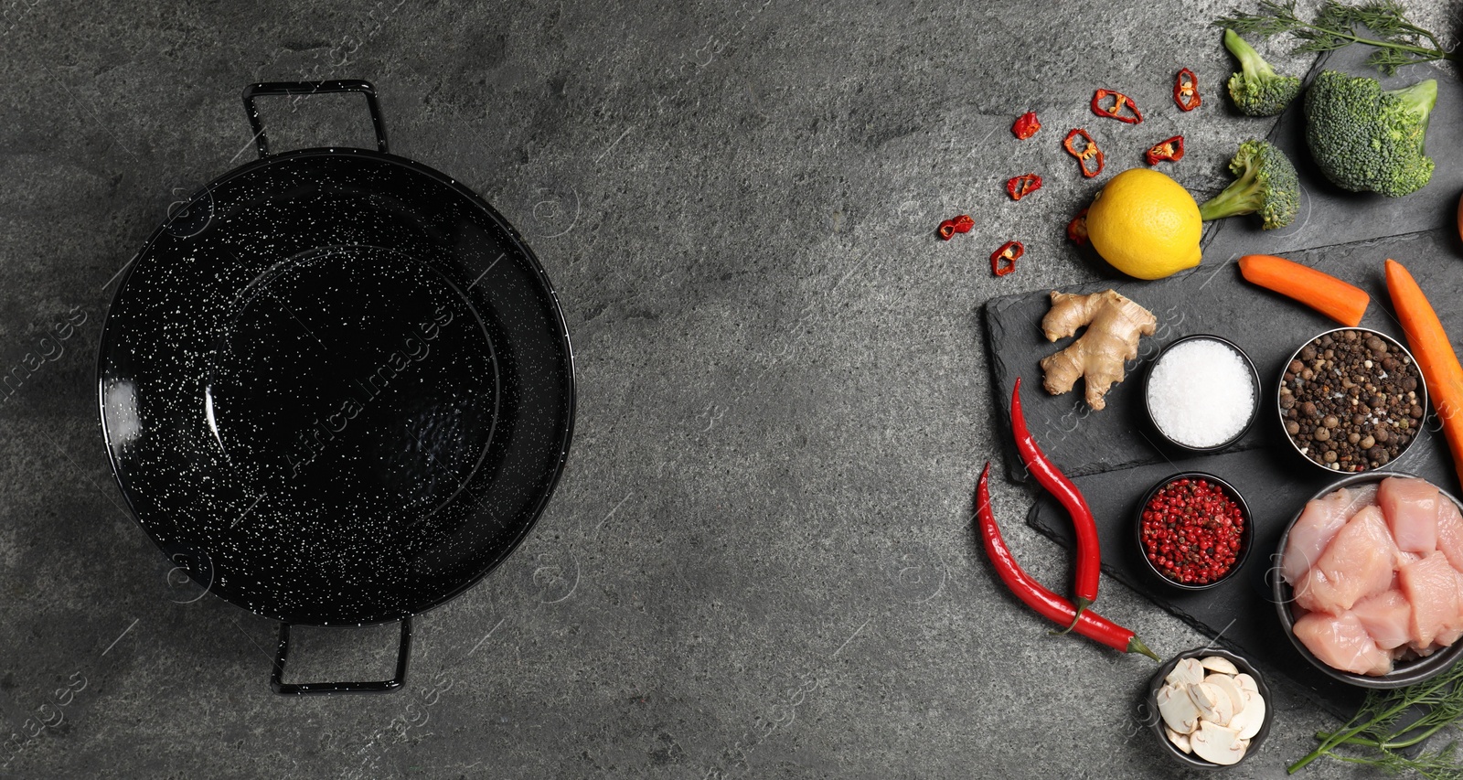 Photo of Empty iron wok and raw ingredients on grey table, flat lay. Space for text