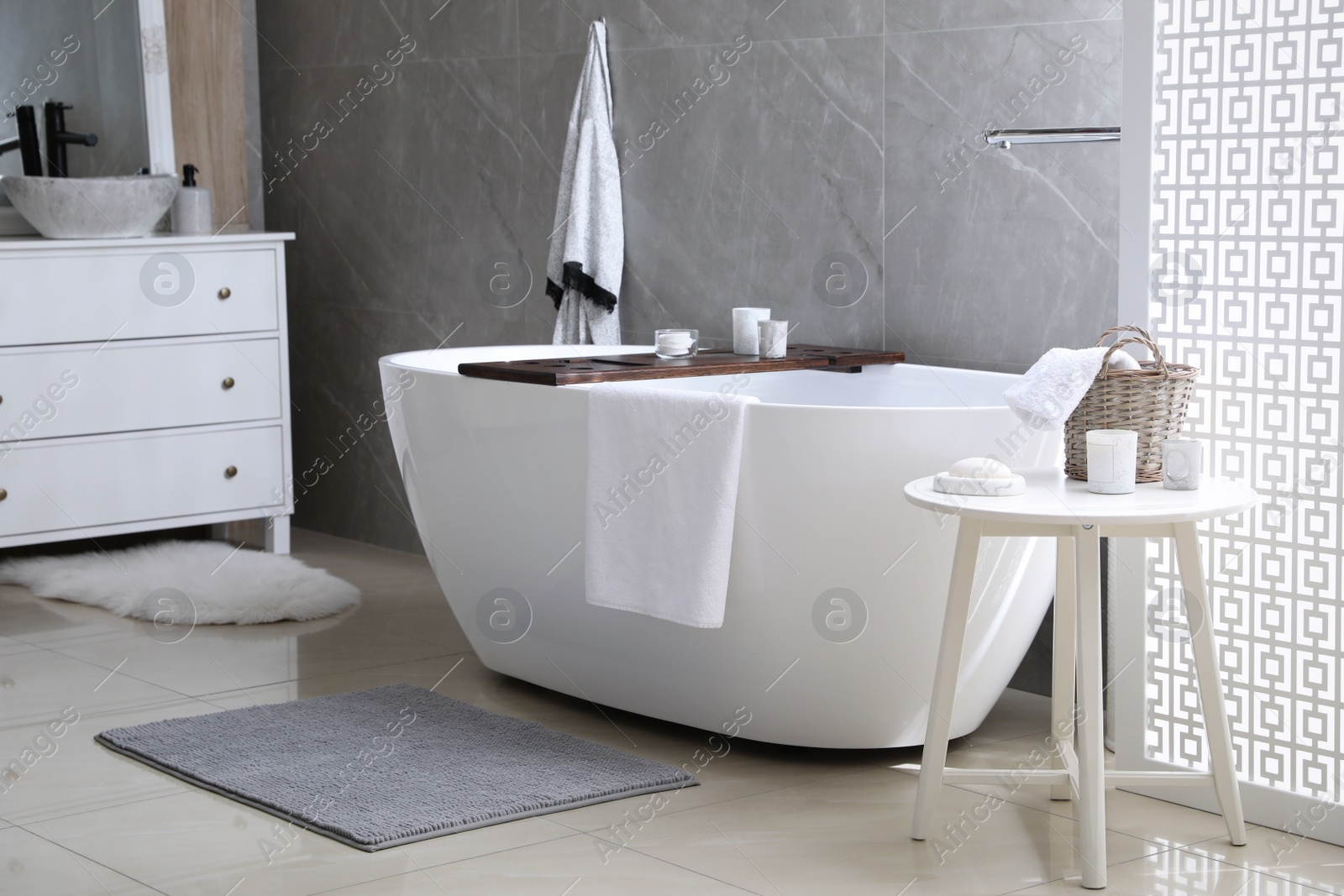 Photo of Modern white tub and chest of drawers with sink in bathroom. Interior design