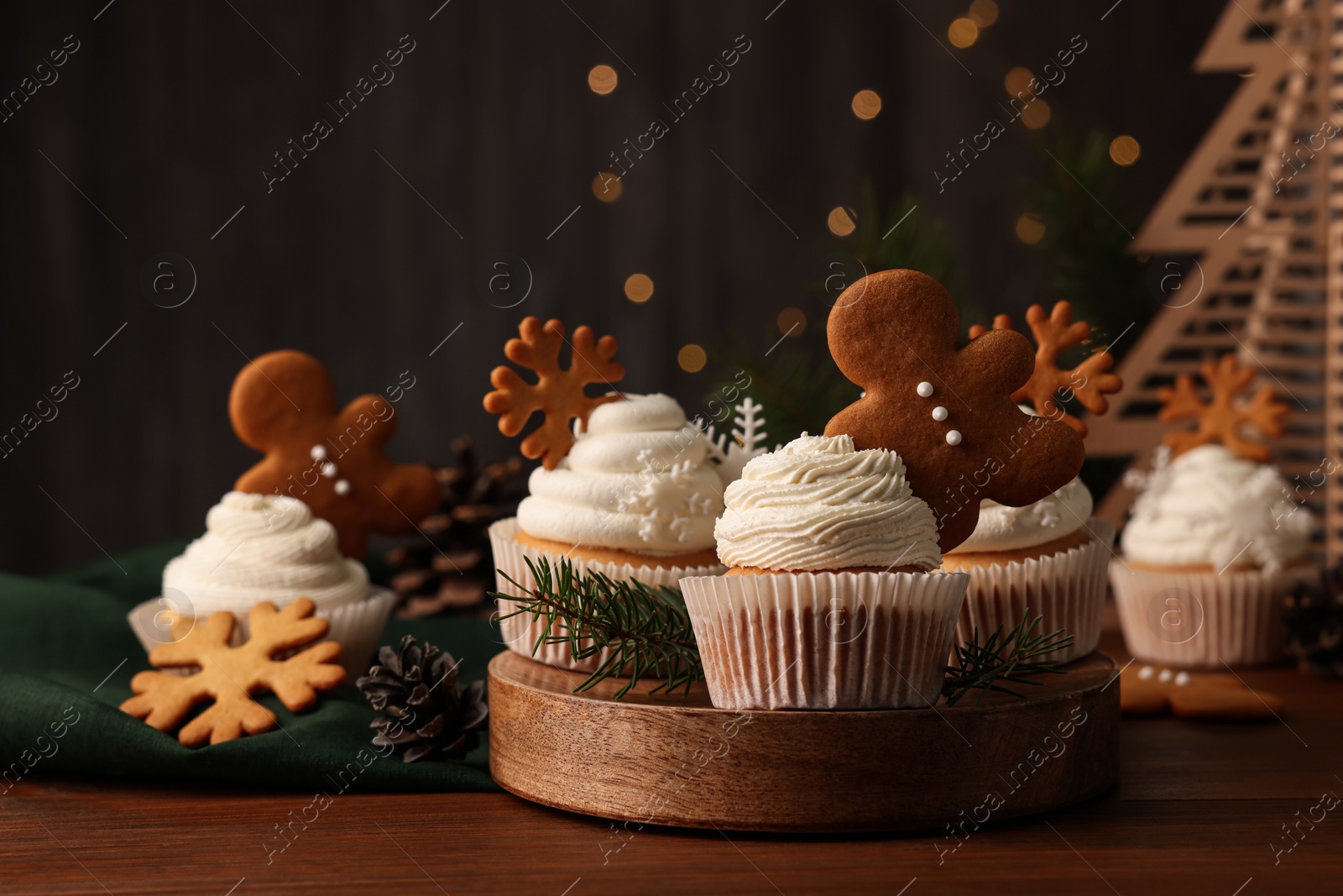 Photo of Different beautiful Christmas cupcakes and fir branches on wooden table. Space for text