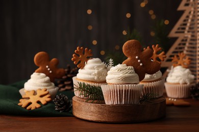 Different beautiful Christmas cupcakes and fir branches on wooden table. Space for text