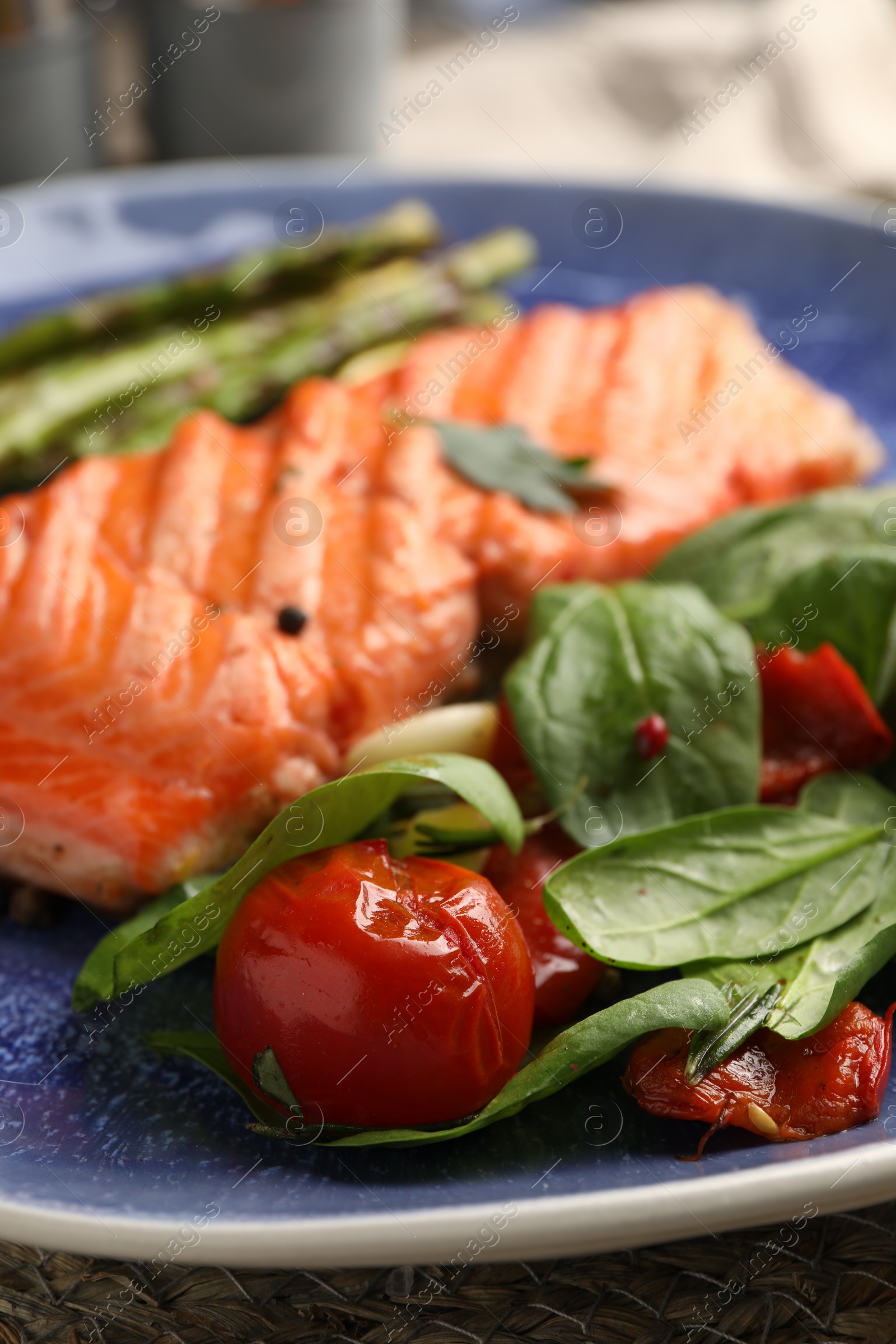 Photo of Tasty grilled tomatoes, spinach and salmon on plate, closeup