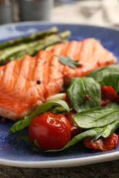 Photo of Tasty grilled tomatoes, spinach and salmon on plate, closeup