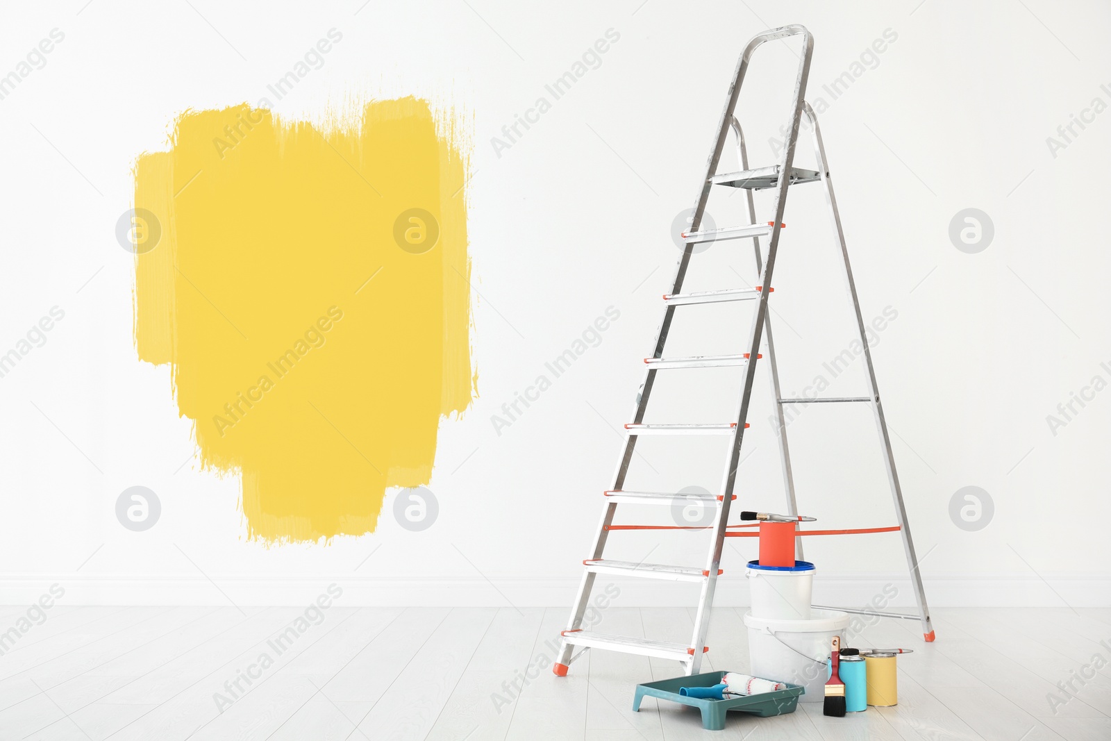 Image of Set with decorator's tools and paint on floor near white wall