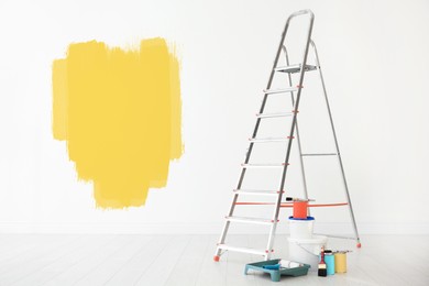 Set with decorator's tools and paint on floor near white wall