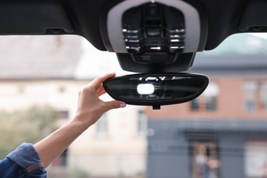 Photo of Woman adjusting rear view mirror inside her car, closeup