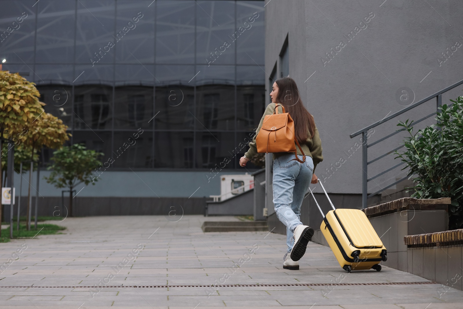 Photo of Being late. Woman with backpack and suitcase walking outdoors, back view with space for text