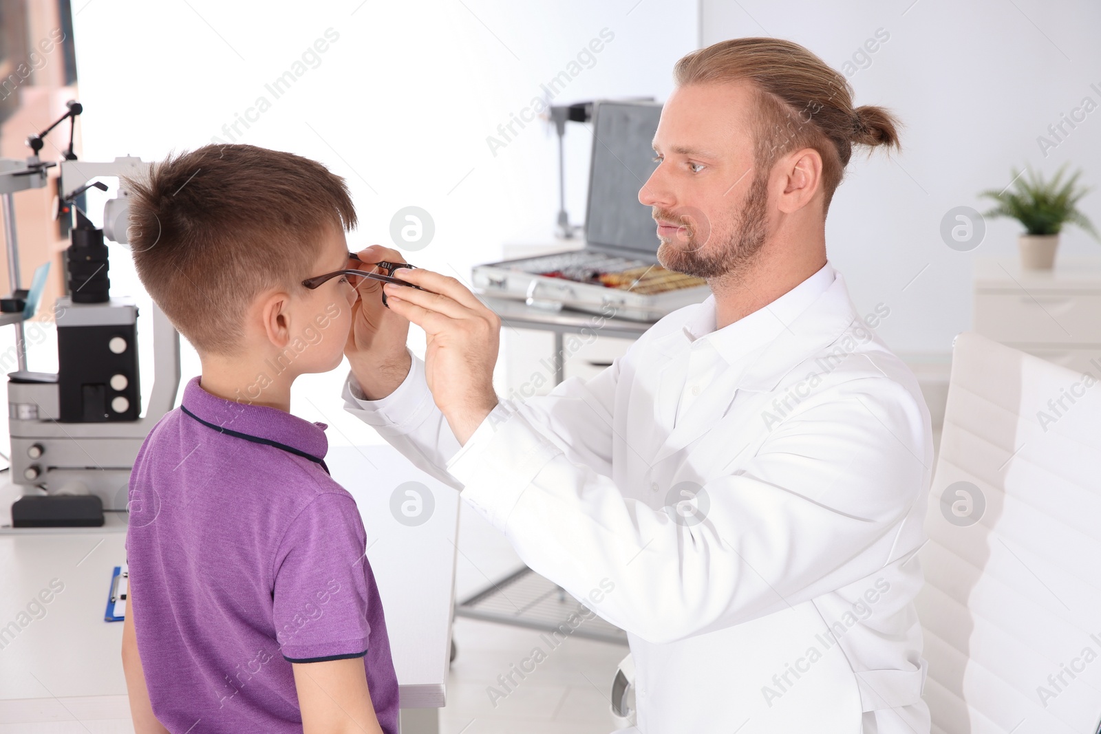 Photo of Children's doctor putting glasses on little boy in clinic