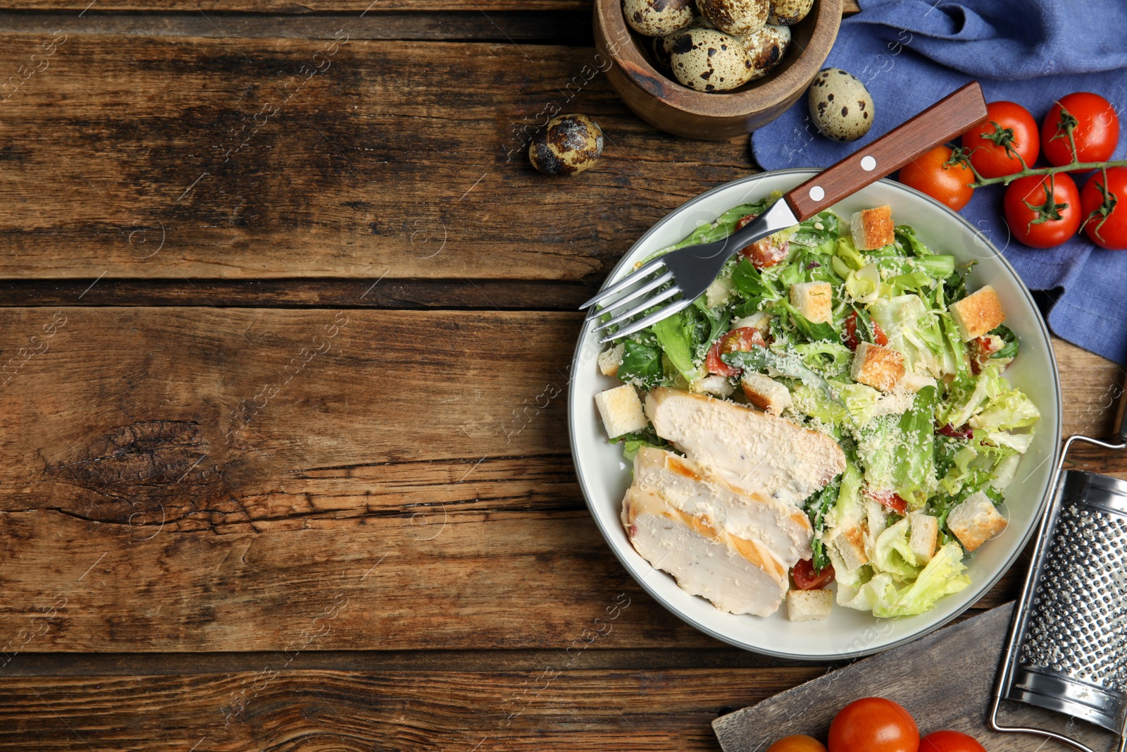 Photo of Delicious Caesar salad in bowl on wooden table, flat lay. Space for text