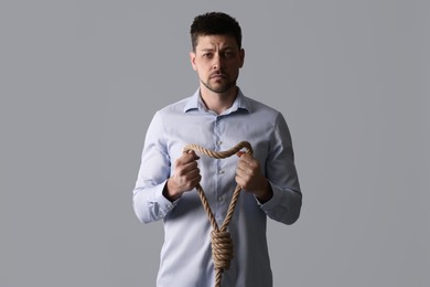 Photo of Depressed man with rope noose on light grey background