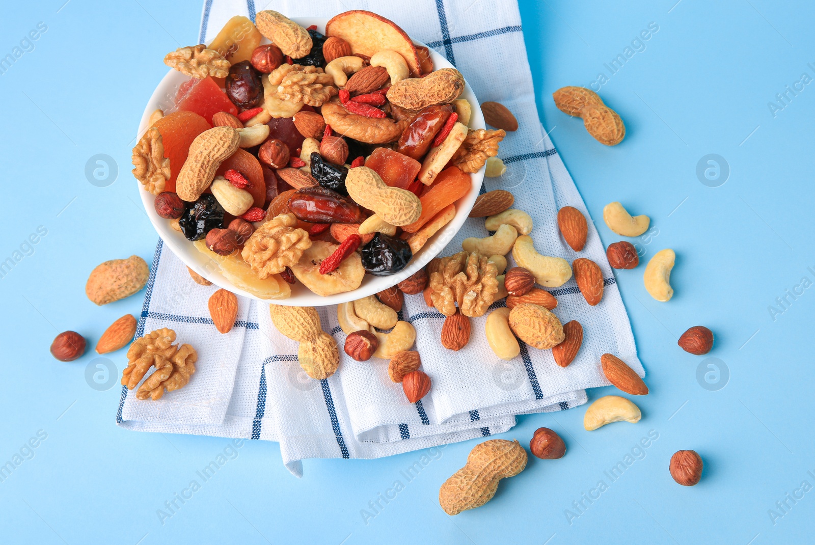 Photo of Bowl with mixed dried fruits and nuts on light blue background, above view