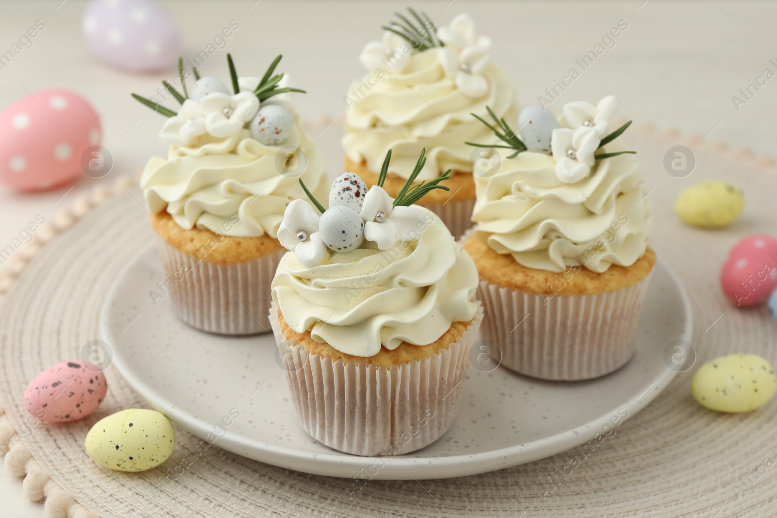 Photo of Tasty Easter cupcakes with vanilla cream and candies on table