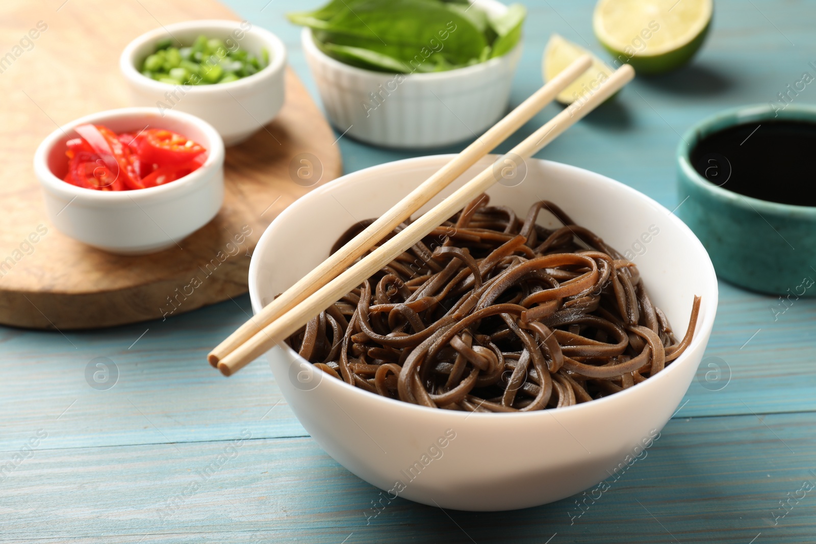 Photo of Tasty buckwheat noodles (soba) served on light blue wooden table