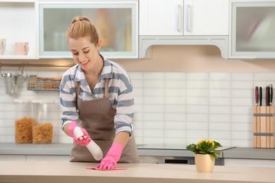 Photo of Woman cleaning table with rag in kitchen
