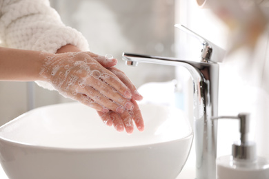 Photo of Woman washing hands with soap over sink in bathroom, closeup