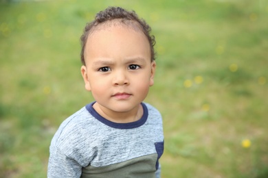 Photo of Cute African-American baby in stylish clothes posing outdoors