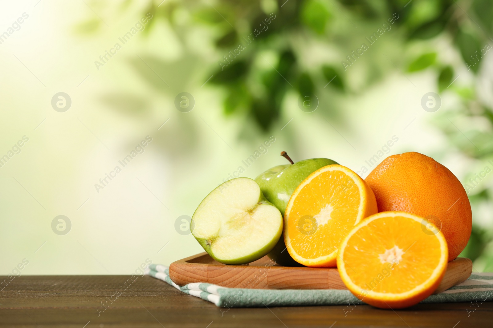 Photo of Fresh oranges and apples on wooden table. Space for text