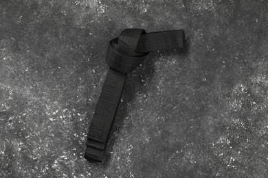 Photo of Black karate belt on gray textured background, top view