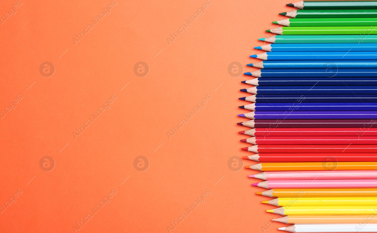 Photo of Color pencils on coral background, flat lay. Space for text