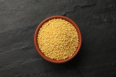 Photo of Millet groats in bowl on black table, top view